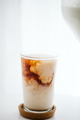 Black tea combining with milk in a glass mug