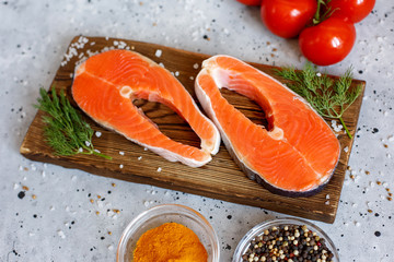 Salmon fillet with spices and vegetables on a grey background. Culinary education. Food background. Healthy food balance. Table background menu. A copy of the space.