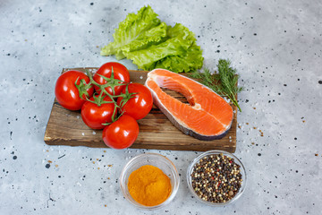 Salmon fillet with spices and vegetables on a grey background. Culinary education. Food background. Healthy food balance.  Salmon steak, raw fish cooked for cooking. on a gray background .Top view