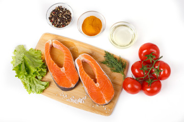 salmon steak with vegetables and spices on a wooden background. The concept of cooking. Grocery background.