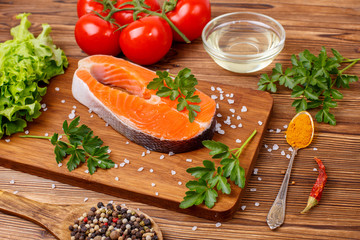 salmon steak with vegetables and spices on a wooden background. The concept of cooking. Grocery background.