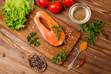 salmon steak with vegetables and spices on a wooden background. The concept of cooking. Grocery background.