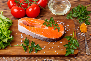 salmon steak with vegetables and spices on a wooden background. The concept of cooking. Grocery background.