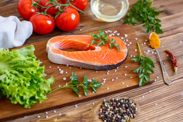salmon steak with vegetables and spices on a wooden background. The concept of cooking. Grocery background.
