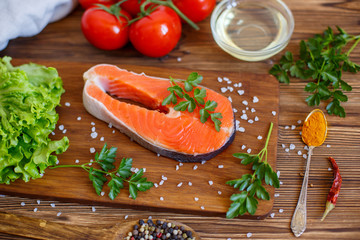 salmon steak with vegetables and spices on a wooden background. The concept of cooking. Grocery background.