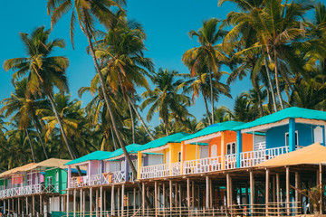 Canacona, Goa, India. Famous Painted Guest Houses On Beach Against Background Of Tall Palm Trees In Sunny Day - obrazy, fototapety, plakaty