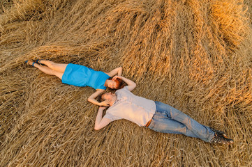 An adult farmer and his wife are lying on rain-covered wheat. A shot taken from the top view.