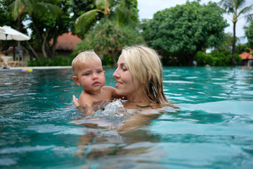 healthy family mother teaching baby swimming pool