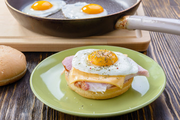 hamburger with egg, cheese and ham on a green plate