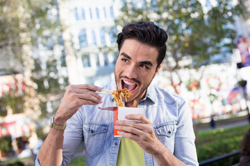 Fototapeta premium Man eating noodles outdoors