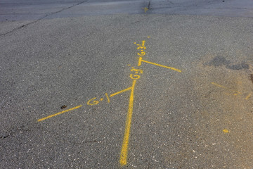 Yellow markings on an asphalt street that show where the utility lines are berried so that they can...