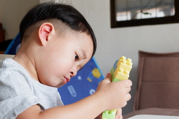Close up of child's hands playing with colorful plastic bricks at the table. Toddler having fun and building out of bright constructor bricks. Early learning. stripe background. Developing toys