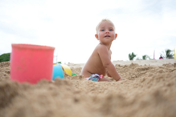cute little girl playing with sand on tropical beach