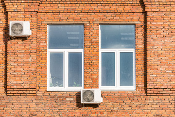 Windows of the old brick building with air conditioning systems.