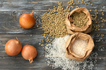 White rice, lentils, onions, ingredients for traditional Middle Eastern food - mujaddara (mjaddra, mejadra, megadarra, mundardara) on wooden table, rustic style, top view