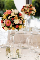 Banquet table decorated with cotton and flower composition, glasses and plates are placed on table