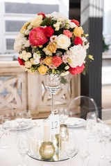 Banquet table decorated with cotton and flower composition, glasses and plates are placed on table