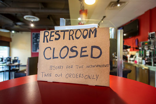 Handwritten sign at restaurant stating Restroom Closed and Take-Out Only and sorry ofr the inconvenience due to coronavirus pandemic.
