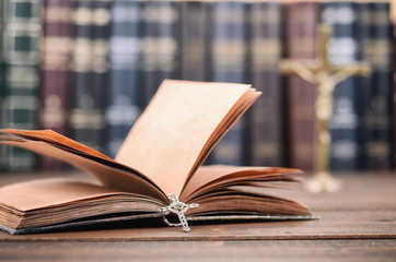 Holy Bible, Christian cross necklace on a wooden background.