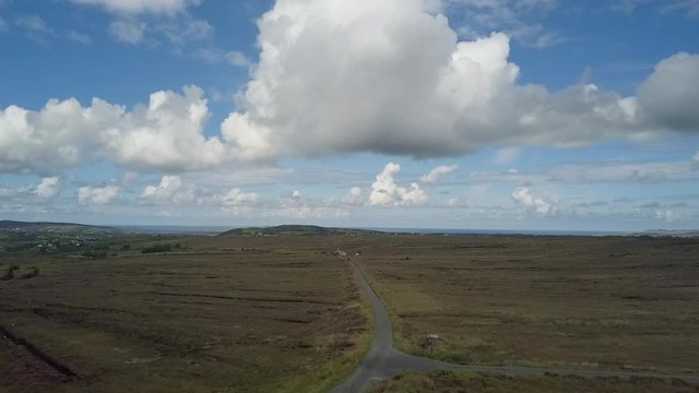 Aerial landscape of mountain road leading to the Irish coast through fields and bogs.