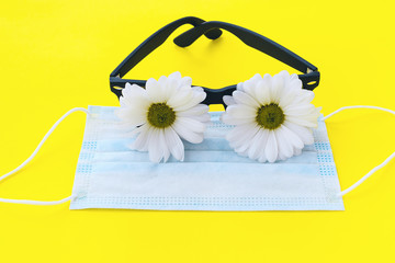 Sunglasses with white chrysanthemum flowers instead of glasses and protective mask on a yellow...