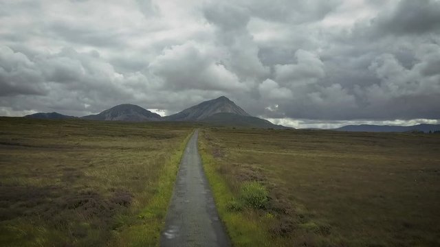 Aerial of mountain landscape under moody clouds following a mountain pass.