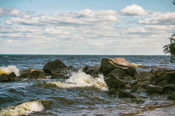 Vintage style image of large boulders, rocks and pebbles at low tide on rocky shore. large pebbles on the beach. Storm at sea, white foam waves