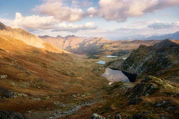 Beautiful mountains at sunset, gold alpine field, lakes and mountain ranges, travel and mountain life