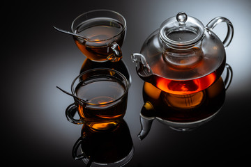 glass teapot and cups with hot tea on table, close view  