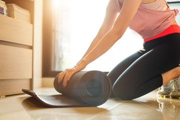 Fitness and yoga concept. Woman is keeping the mat after studying yoga and practicing meditation and stretching the muscles after a hard workout.