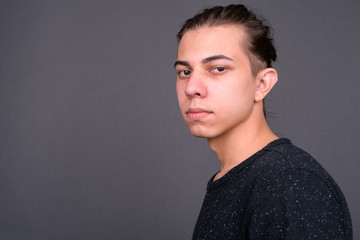 Closeup profile view of young handsome man with hair tied looking at camera