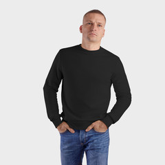 Fototapeta premium Template of black blank sweatshirt on a man in blue jeans with hands in pockets, textile heather isolated on a white background.