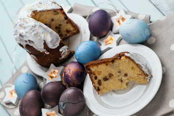 Spring holiday of Easter. Cake and painted chicken eggs. A piece of birthday cake. Garlands in the form of stars. Pie on a table made of blue boards.