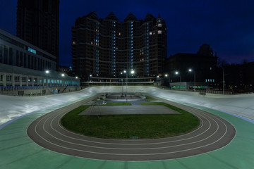 Illuminated night bicycle stadium and city skyline in the background