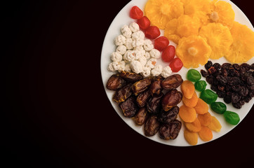 colored dried fruits on a white plate, on the table for a healthy Breakfast, top view