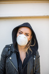 Junge Frau mit Lederjacke trägt Maske Sprayer, Corona, Schutz, Selbstschutzmaske, Vermummung, Blond