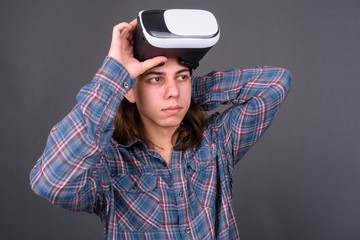 Young handsome hipster man with long hair using virtual reality headset