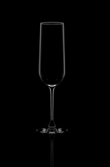 a glass champagne glass stands on a black background