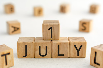 July 1 - from wooden blocks with letters, important date concept, white background random letters around