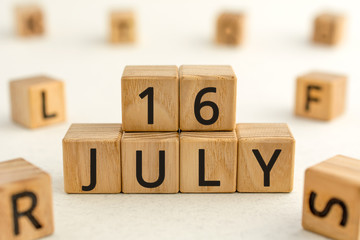 July 16 - from wooden blocks with letters, important date concept, white background random letters...