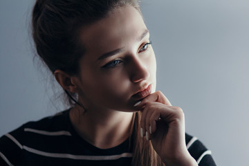 portrait of a beautiful pensive girl with makeup on gray studio isolated background, cyoung woman thinking, concept beauty and life