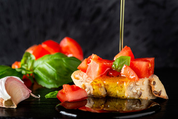 Pouring olive oil over a bruschetta with tomatoes