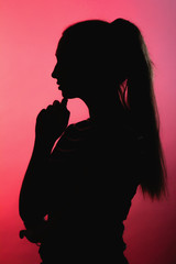 silhouette of thoughtful girl on red lightened background, unrecognizable woman face profile, concept emotions, stress