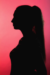 silhouette of thoughtful girl on red lightened background, unrecognizable woman face profile, concept emotions, stress