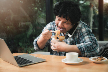 A man who works from home is busy talking on the phone with colleagues about work and eating instant noodles. While his eyes stared at the work content on the laptop as well.