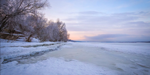 Winter landscape at dawn, riverbank of a frozen ice.