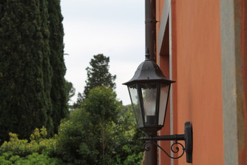 Metal lamp on wall in garden with tree background, electric lamp are used as decoration and for lightening in home and garden