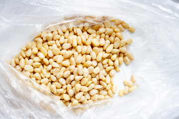 Peeled pine nuts in a plastic bag on a white background