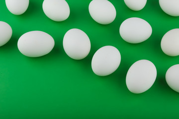 group of chicken eggs on green background top view with copy space
