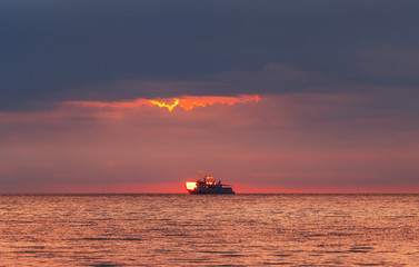 A ship at sea caught the sun. Sea sunset.